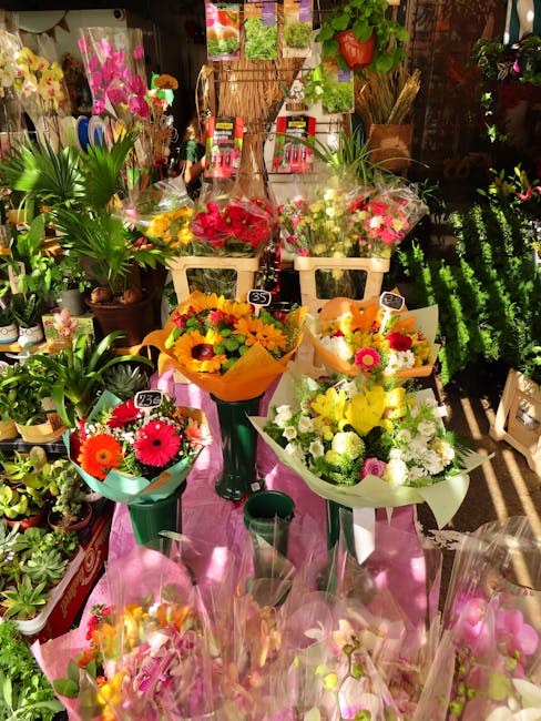 A vibrant display of fresh floral bouquets arranged on a pink table within Beddingtonflowers.co.uk shop. The arrangement features colorful flowers including pink gerbera daisies, yellow sunflowers, wh